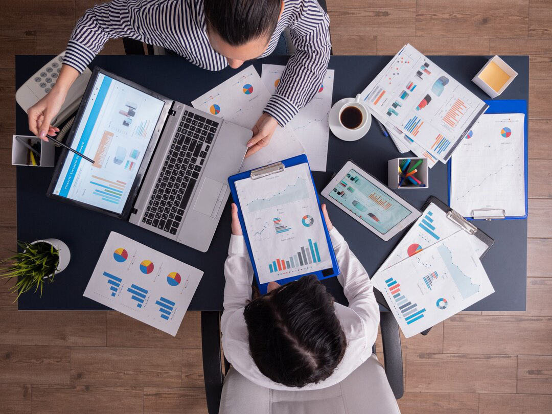Top viewtop view of manager and employee doing teamwork in business office , looking at charts on laptop display Top viewtop view of manager and employee doing teamwork in business office , looking at charts on laptop display<br />